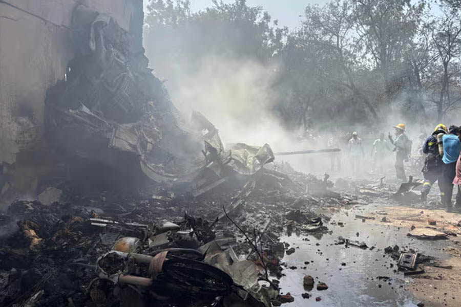 People stand around debris at the site of an aircraft that crashed in India's northwestern city of Ahmedabad in Gujarat state.