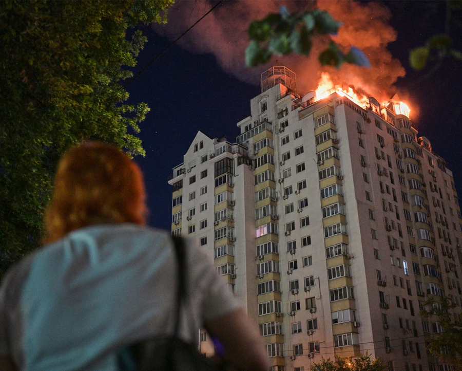 A woman looks at an apartment building burning after a Russian missile attack in Kyiv, Ukraine.