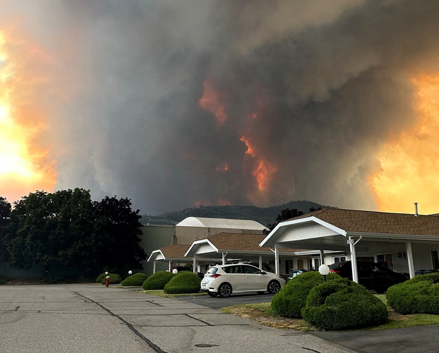 Smoke rises from the Bald Range wildfire over a residential street in Summerland, British Columbia, on 7 August. The fast-moving fire forced more than 20,000 people to evacuate.