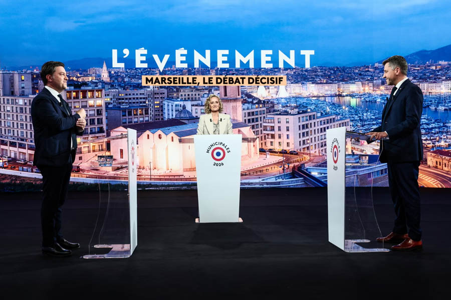 Benoît Payan and Franck Allisio participating in a televised political debate moderated by Caroline Roux before Marseille local elections 2026