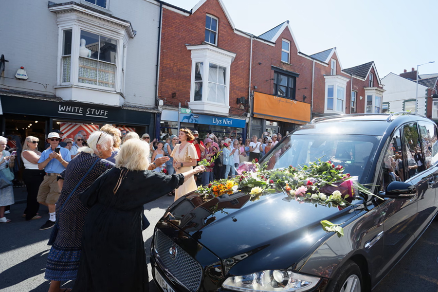 Fans pay their respects by placing flowers on the hearse carrying Welsh singer Bonnie Tyler as it travels along Newton Road to her home in Llwynderw, Mumbles, Wales