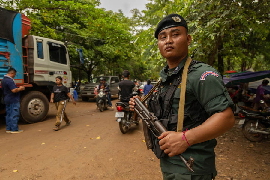 A Cambodian officer stands watch at a refugee resettlement camp in Oddar Meanchey on Sunday, as thousands flee escalating border violence ahead of Monday's peace talks with Thailand.