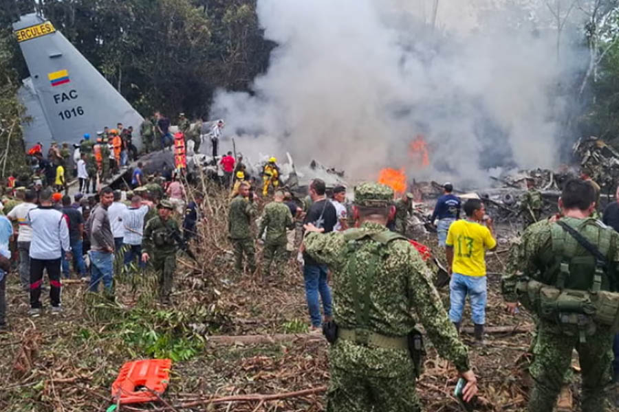 Emergency responders and soldiers at the site of a crashed Colombian military transport plane in the Amazon region, with smoke, debris, and rescue operations underway near Puerto Leguízamo.