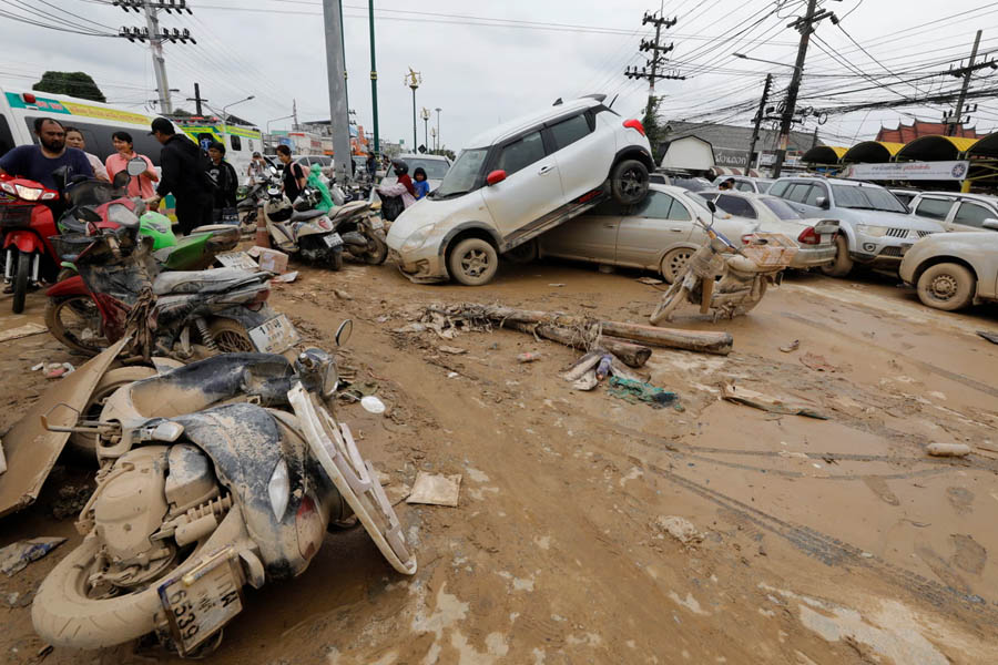 Damaged cars and motorbikes scattered across a muddy street as floodwaters recede in Hat Yai, southern Thailand.