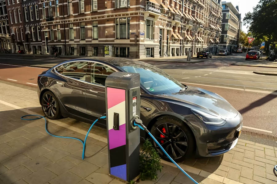 An electric vehicle plugged into a charging station on a city street in Amsterdam, Netherlands, as European automakers face mounting pressure from Chinese rivals and softening EU emissions targets.