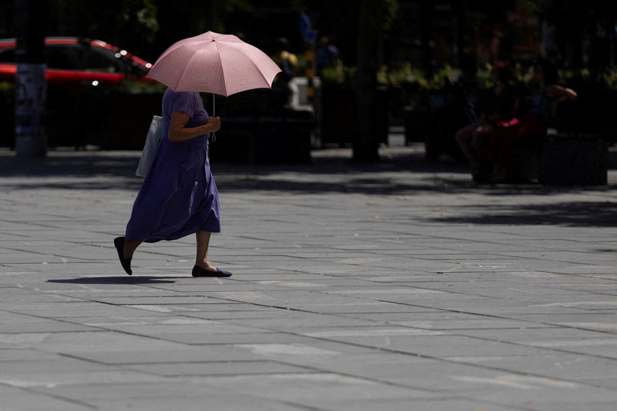 A woman uses umbrella to hide from the sun during heatwave in Belgrade, Serbia