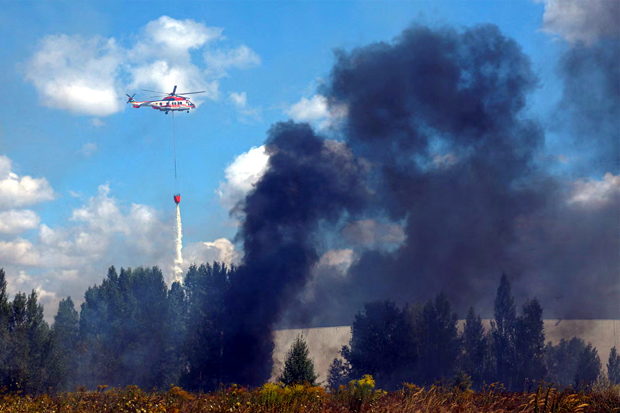 A firefighting helicopter drops water over a food warehouse damaged during Russian drone strikes near Kyiv, 12 August 2026.