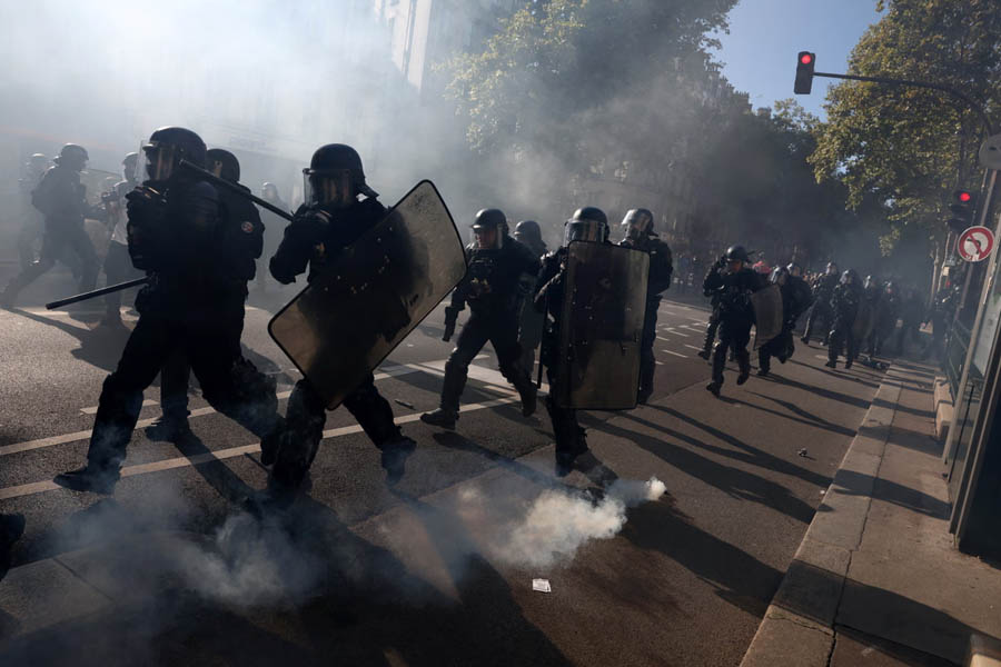 French riot police advancing amid teargas during clashes with protesters in Paris demonstration, as France sees mass arrests and unrest over budget cuts.