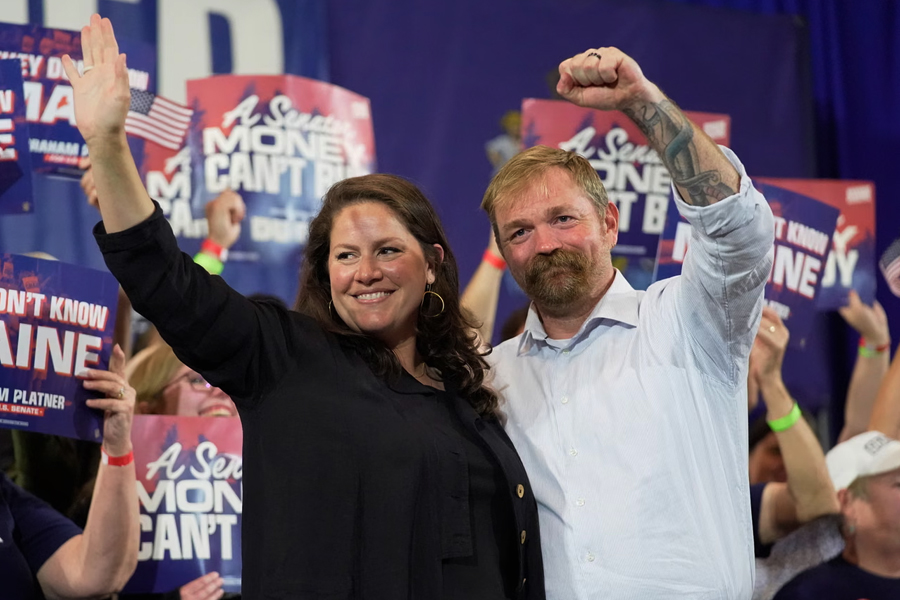 Graham Platner, right, and his wife Amy Gertner gesture to supporters during a primary election night watch party. Platner won 72% of the vote despite facing multiple personal misconduct allegations.