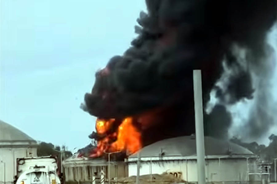 An industrial building and a fuel tanker in Haifa, Israel, damaged by debris from an intercepted missile, with emergency response teams on site.
