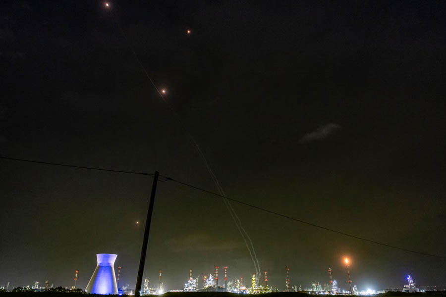 Missile defense interceptor trails and gas flares illuminate the night sky over an oil refinery in Haifa, northern Israel, during heightened security operations.