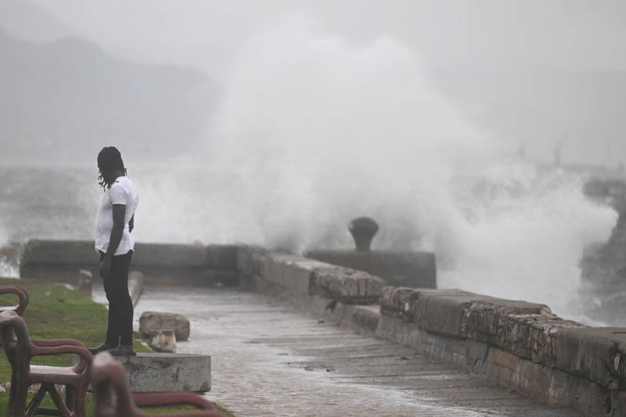 A man standing at Kingston Waterfront watching large waves crash against the seawall ahead of Hurricane Melissa’s landfall in Jamaica.