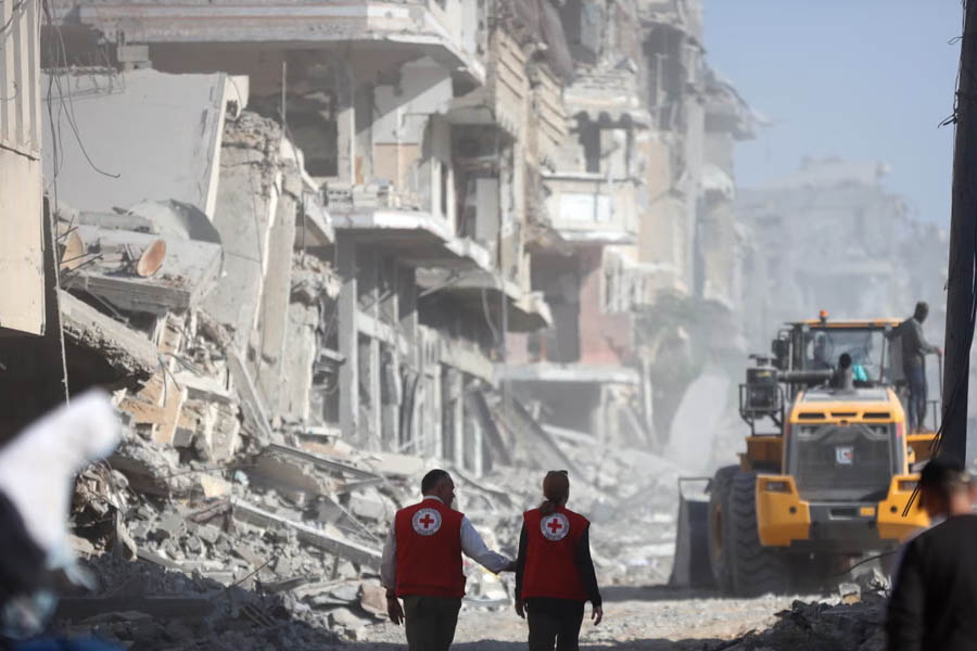 ICRC members watch an excavator digging during a search for bodies in the al-Tuffah area of Gaza City.