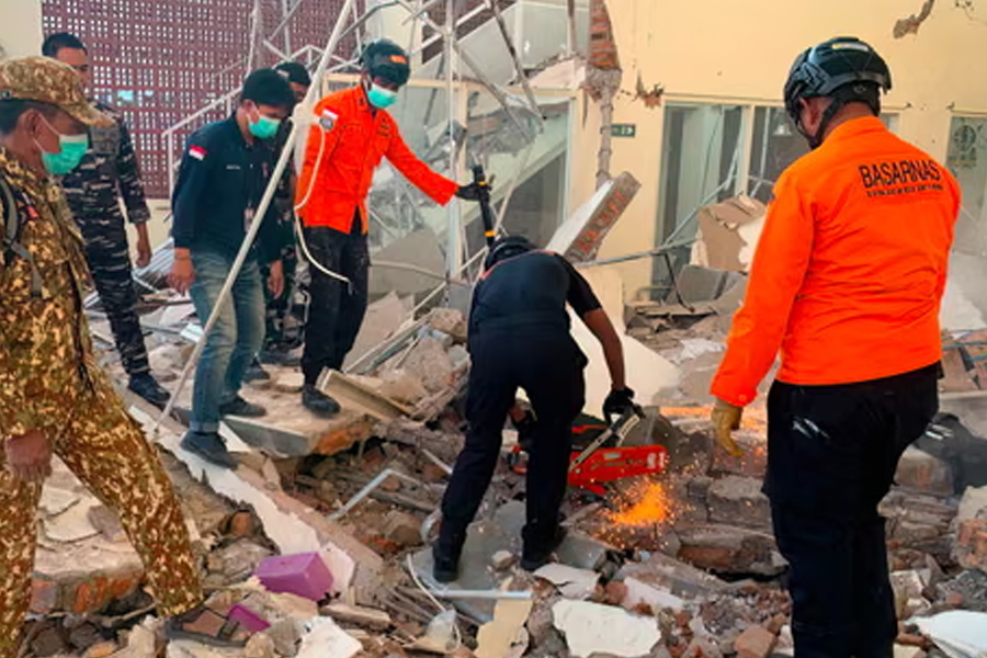Rescuers working amid the rubble of damaged building in Maumere