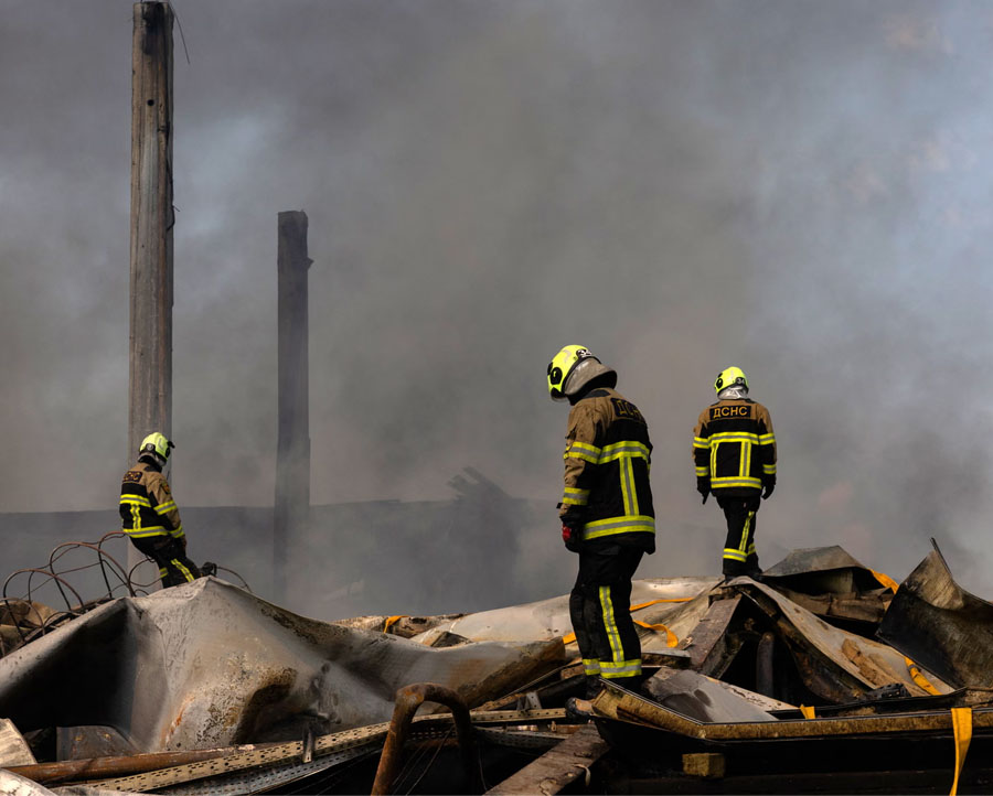 Ukrainian firefighters work to put out a fire following a massive Russian ballistic missile and drone strike on Kyiv.