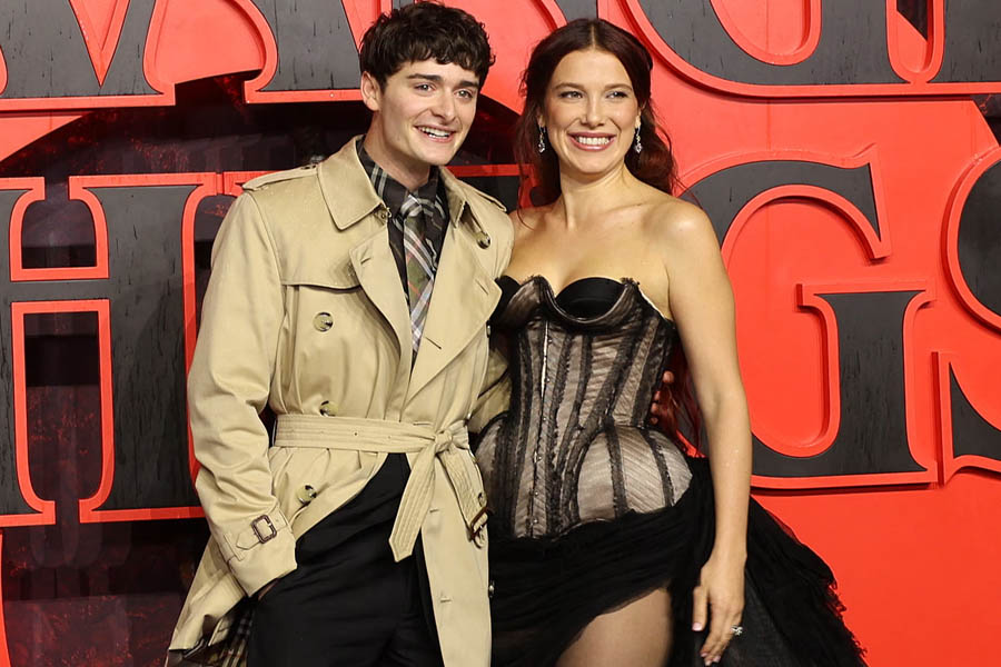 A photo of Noah Schnapp and Millie Bobby Brown standing together at Leicester Square in central London, smiling during a public appearance.