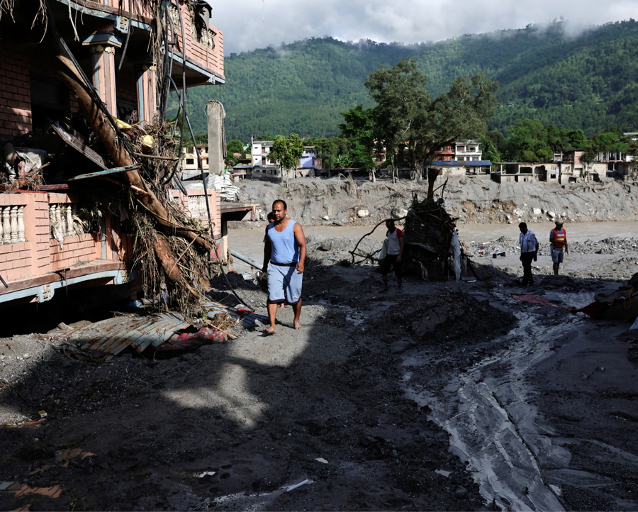 People move through a mud-covered road in Trishuli in Nepal's Nuwakot district.