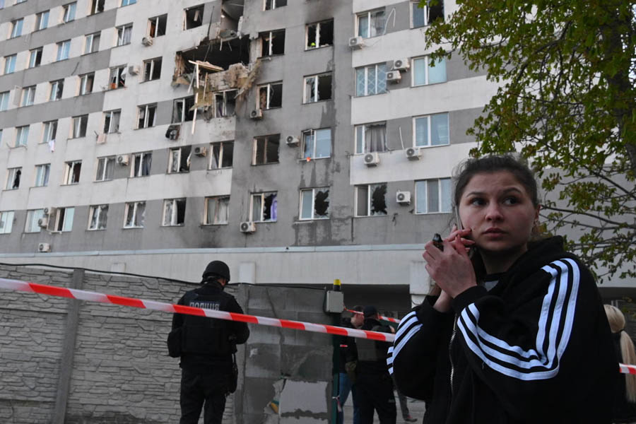 A woman speaks via a phone in front of a residential building which was damaged after a Russian drone strike on Odesa.