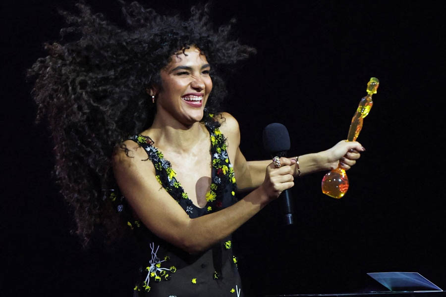 Olivia Dean holding her Artist of the Year trophy on stage at the Brit Awards 2026 in Manchester after winning Best Pop Act and Artist of the Year.