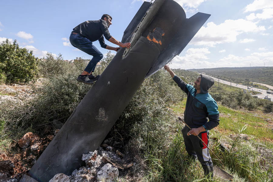 Palestinian man climbing on wreckage of Iranian missile in West Bank village of Hares, Israel.