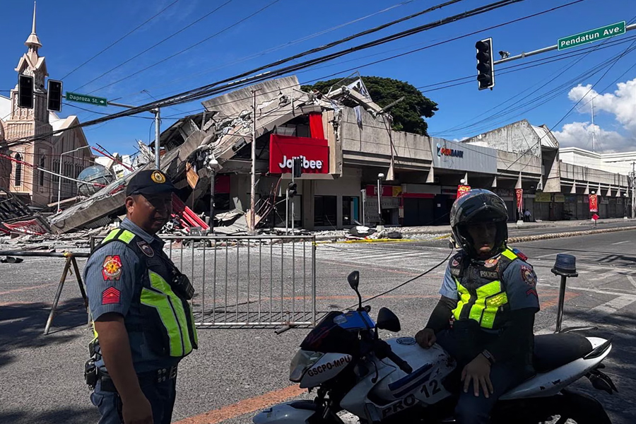 Police gather in front of a collapsed Jollibee fast food restaurant after a magnitude-7.8 earthquake in General Santos City, Philippines