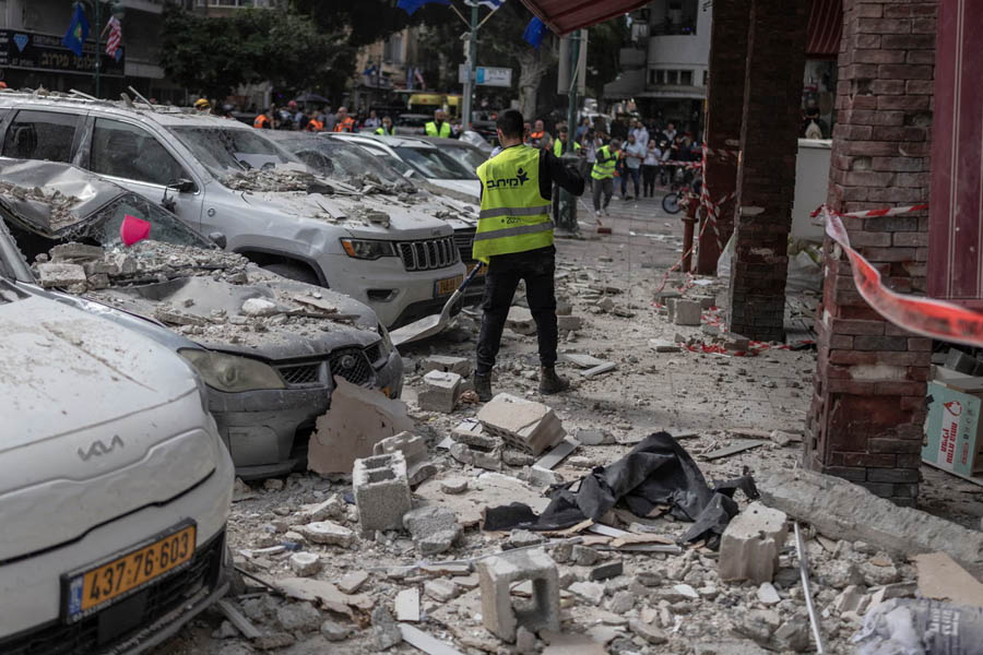 Municipal workers clean the street at a building that was hit by an Iranian projectile attack in Ramat Gan, central Israel, as tensions ease following a two-week ceasefire announcement.