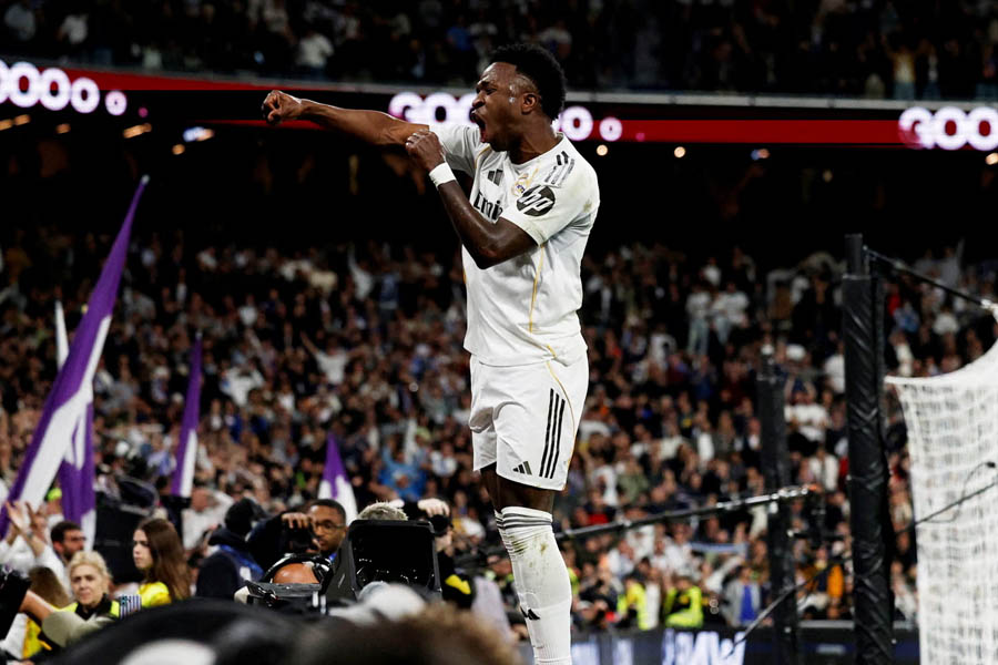 Vinícius Júnior of Real Madrid celebrates his third goal against Atlético Madrid with fans cheering in the background.