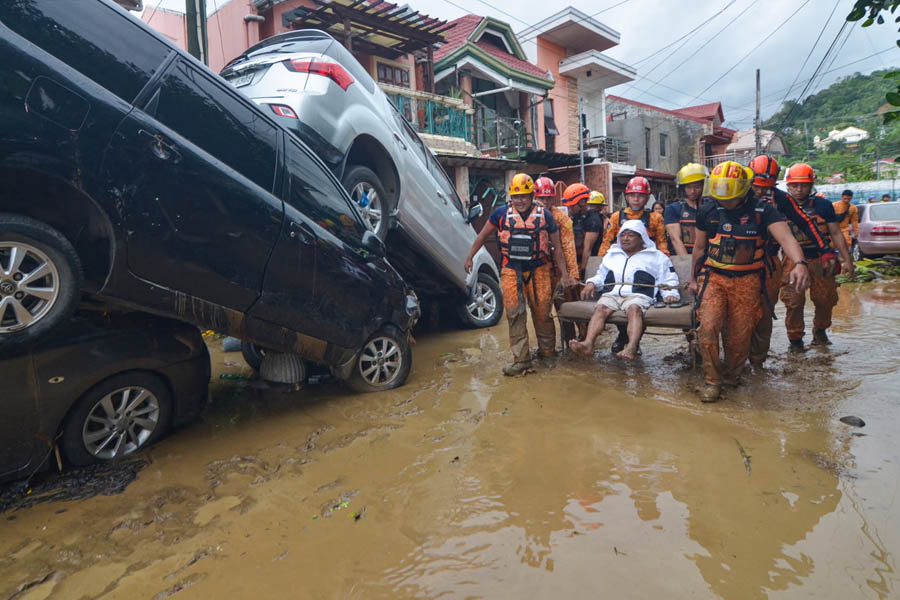 Rescuers carrying a resident past submerged cars in floodwaters during Typhoon Kalmaegi in Cebu City, central Philippines.