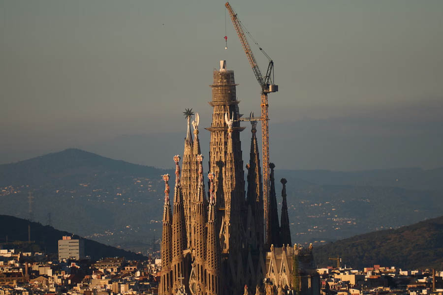 The Sagrada Familia basilica in Barcelona with cranes lifting a section of its central tower, marking its rise as the world’s tallest church.