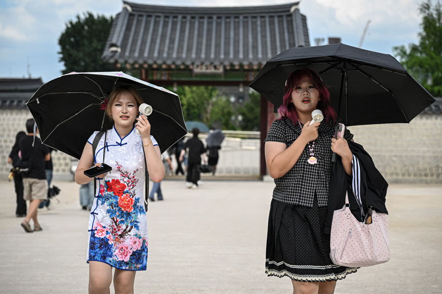 Women use portable fans to cool off at the Gyeongbokgung Palace in Seoul in July