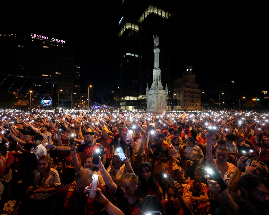 Spain's supporters turn on their phone flashlights as they watch the match on giant screens underneath the Christopher Columbus statue on Plaza de Colon in Madrid.