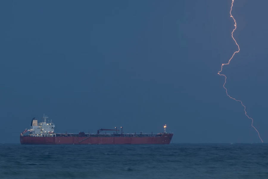The tanker Rarity anchored near Sultan Qaboos port in Muscat, Oman, with port infrastructure visible in the background.