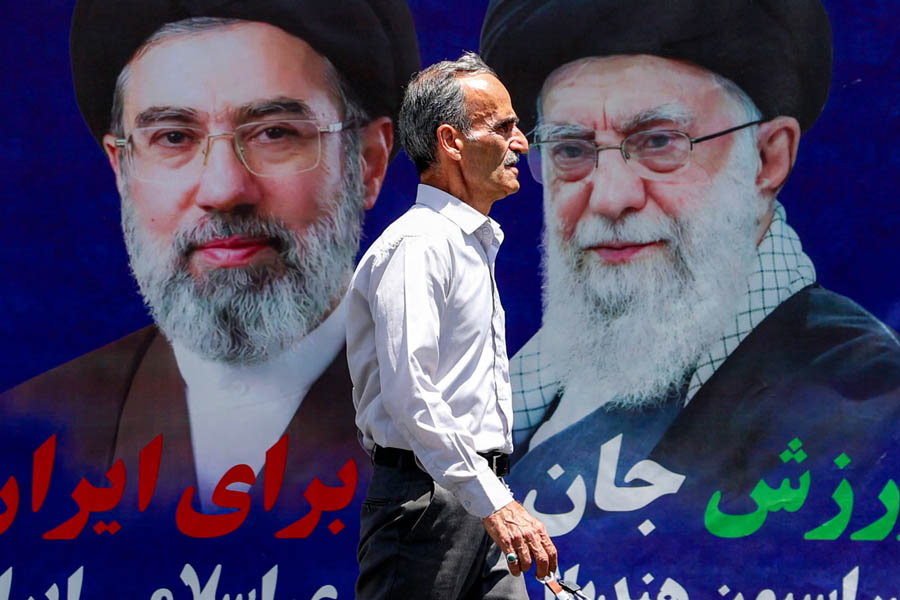 A man walks past a large banner depicting Iran's current supreme leader Mojtaba Khamenei (L) and late father Ali Khamenei along a street in Tehran on 6 May 2026.