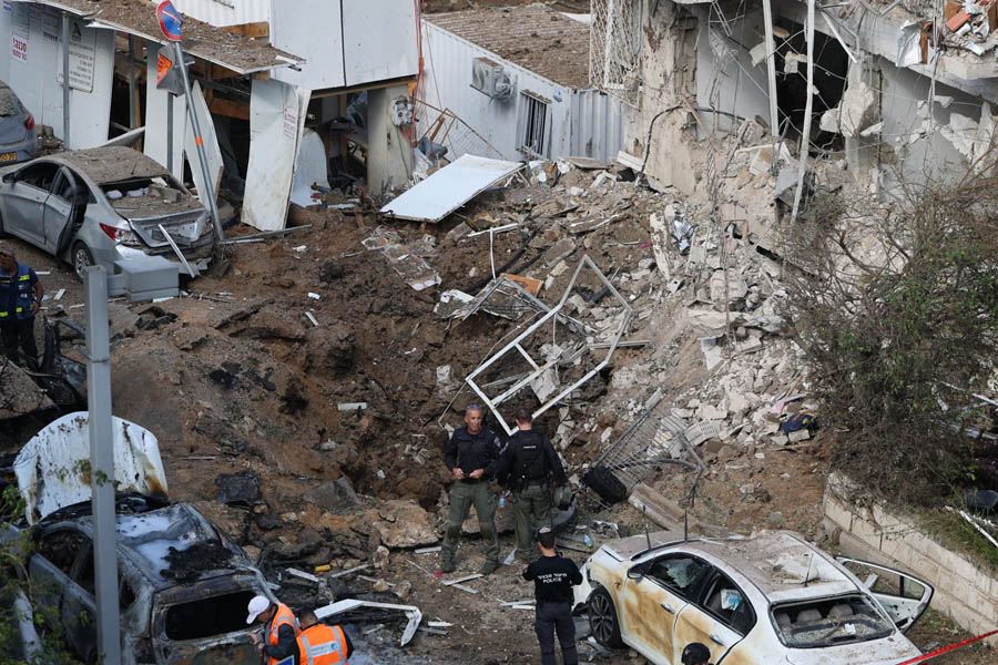 Israeli rescue personnel and emergency vehicles at the scene of a missile strike in Tel Aviv, with visible destruction to buildings and scattered debris following an Iranian attack on March 24, 2026.