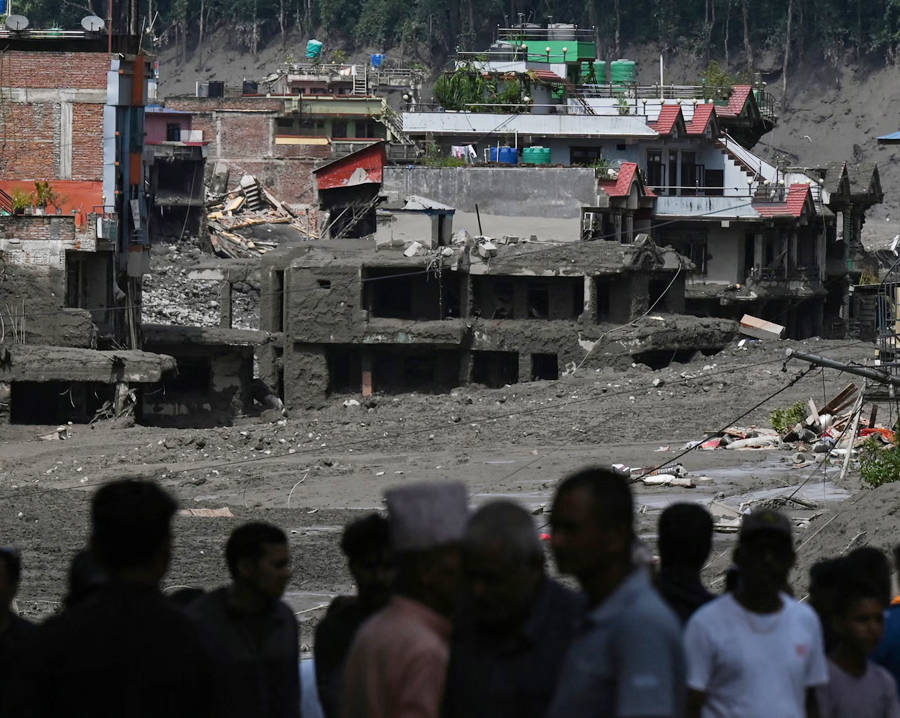 Residents look at buildings submerged by mud after the flash flooding and landslide disaster in Trishuli Bazar in Nepal's Nuwakot district.
