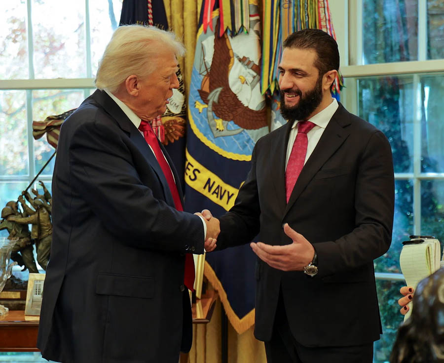 Donald Trump and Ahmed al-Sharaa shaking hands in the White House during a historic summit to discuss partial suspension of US sanctions on Syria.