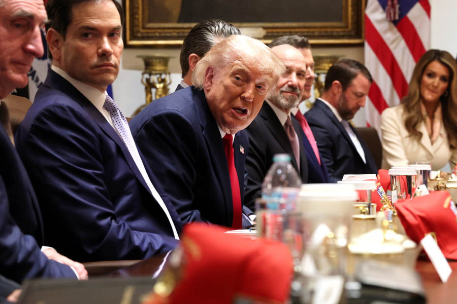 President Donald Trump seated at the head of a table with cabinet members during a White House cabinet meeting, discussing Iran policy and Middle East strategy.