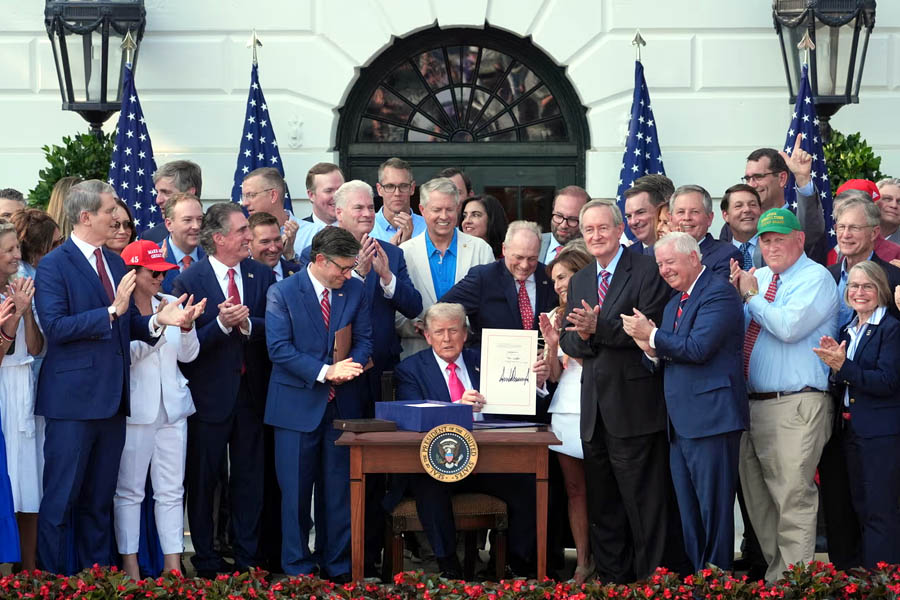 Surrounded by members of Congress, President Donald Trump signs his landmark tax-and-spending bill at the White House on Friday, marking a major political victory that cuts safety-net programs and boosts immigration enforcement.