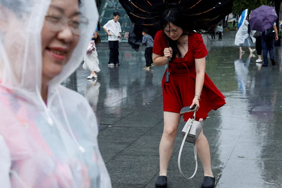 A woman's umbrella is battered by strong winds as Typhoon Dolphin brings powerful winds and heavy rain.