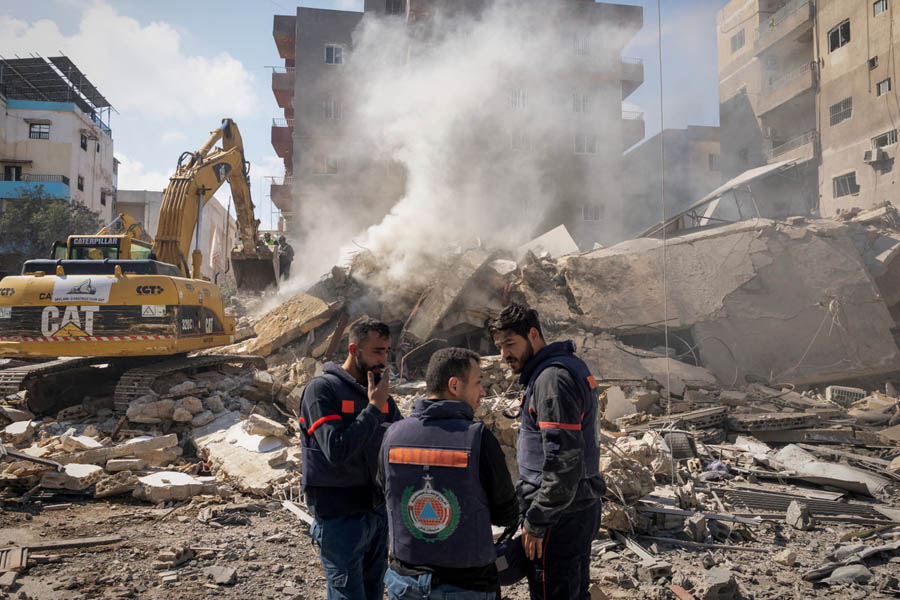 Rescue workers stand next to the rubble at the site of an Israeli strike in Tyre.