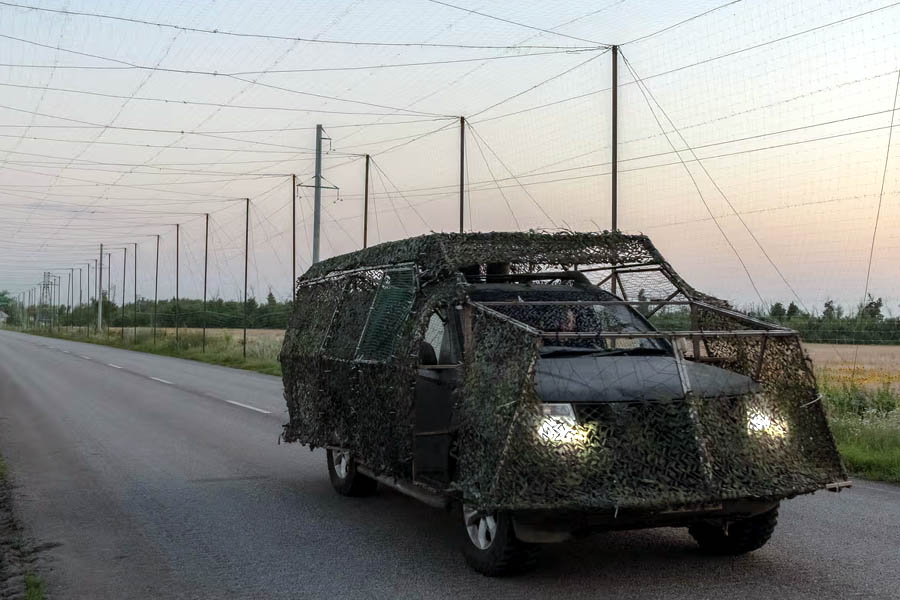 A Ukrainian military vehicle with anti-drone protection moves through Donetsk amid global tensions over weapons delays and drone attacks.
