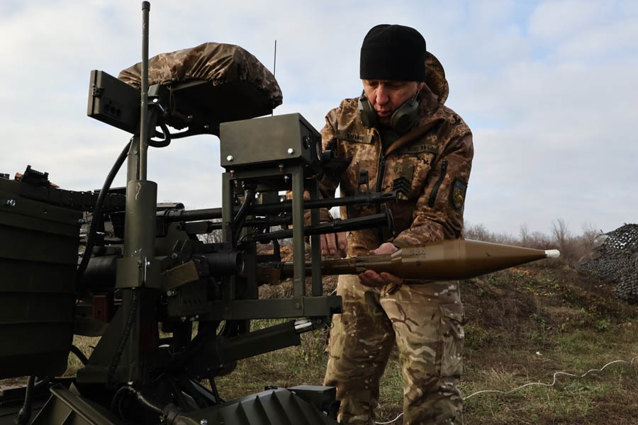 Ukrainian soldier fitting a warhead onto a land drone in the Zaporizhzhia region amid ongoing military activity.