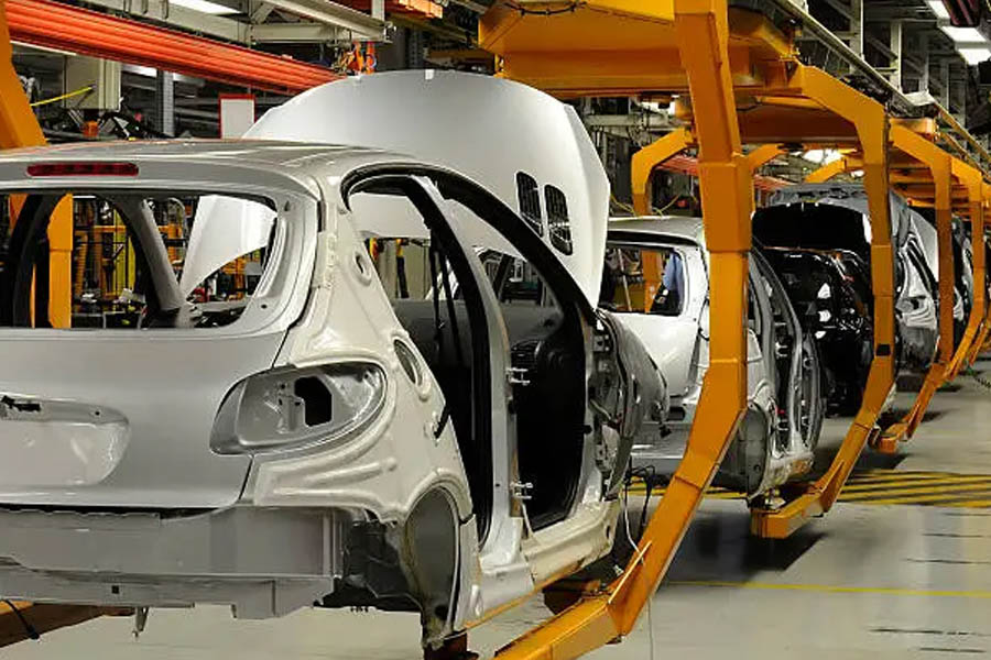 Factory workers assembling Volkswagen ID.4 electric vehicles on a production line in Emden, Germany, with partially completed cars moving along the conveyor.