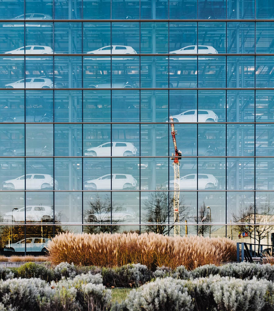 The iconic glass-walled VW Transparent Factory in Dresden, Germany, with its modern architecture and illuminated interior visible from the outside.
