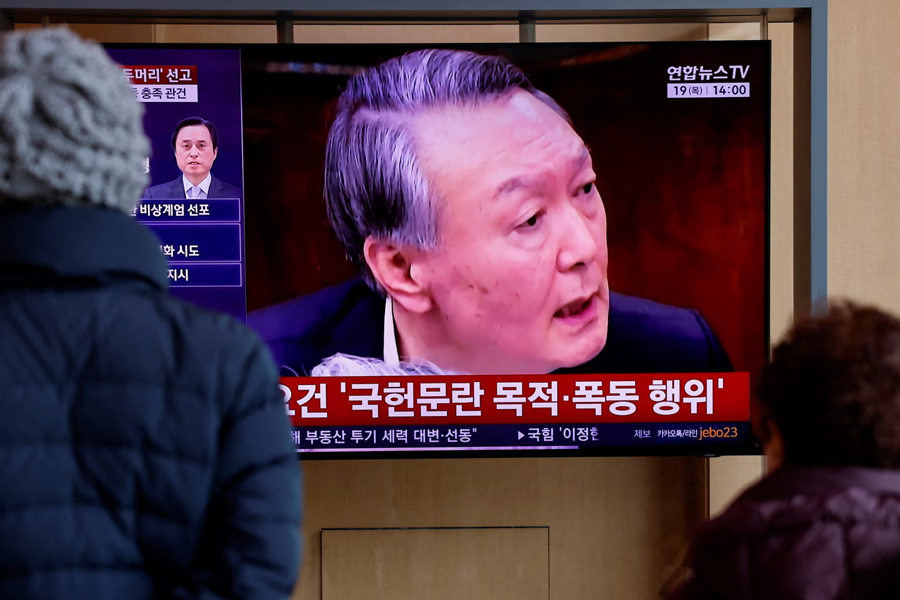 People watch a news report on the sentencing trial of South Korea's former president Yoon Suk Yeol. The Seoul Central District Court sentenced the ousted leader to 30 years in prison for sending drones over Pyongyang.