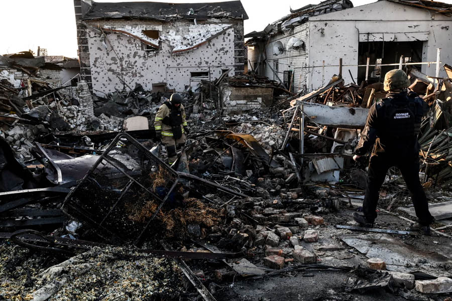 Rescuers working at the site of destruction following a Russian air strike in Zaporizhzhia, Ukraine, with damaged buildings and debris visible.